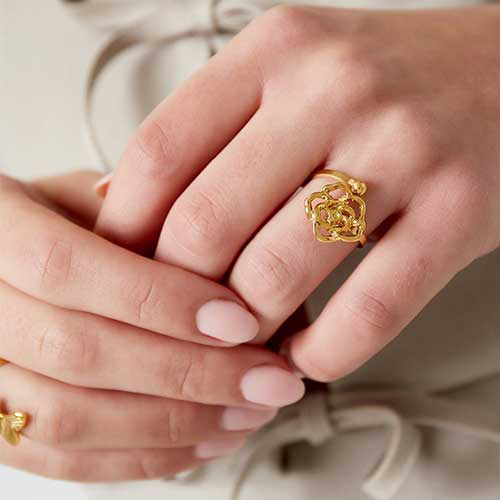 Goudkleurige stainless steel ring met open bloem en bolletje - minimalistisch en romantisch ontwerp.