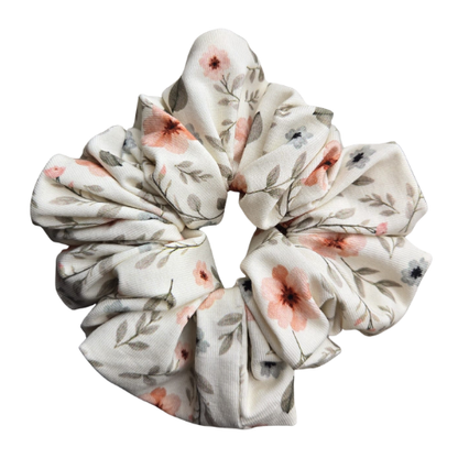 Handgemaakte katoenen scrunchie met bloemenprint, met licht roze en blauwe anjerbloemen op een zachte cremé achtergrond, stevige grip voor het haar
