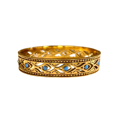 Gesloten goudkleurige stainless steel bangle met blauwe details – stijlvolle en moderne damesarmband met kleurrijk accent op witte achtergrond