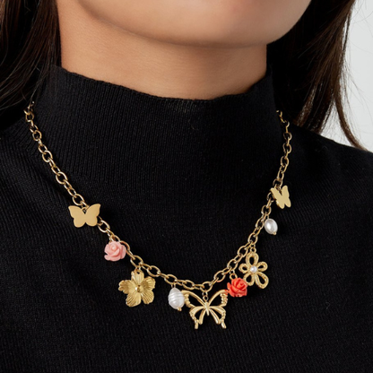Goudkleurige bedelketting met vlinder- en bloemenbedels en twee gekleurde bloemen als statement detail gedragen om de hals