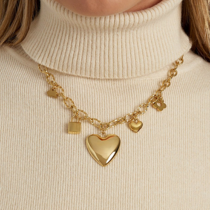Goudkleurige stainless steel bedelketting met hartjes en slotje bedels om de hals gedragen