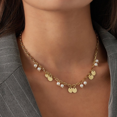 Trendy zilverkleurige ketting van stainless steel met munten en parels gedragen om de hals