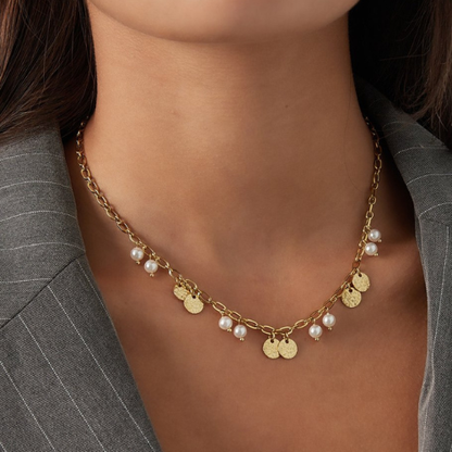 Trendy zilverkleurige ketting van stainless steel met munten en parels gedragen om de hals