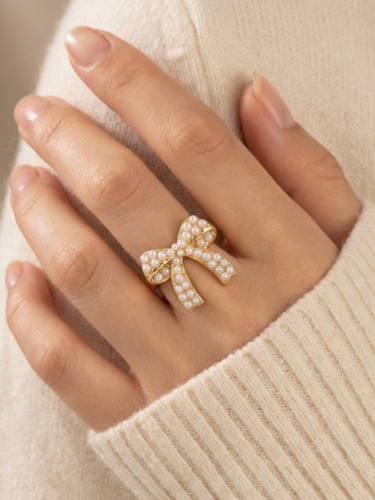 Goudkleurige stainless steel ring in de vorm van een strik ingelegd met pareltjes