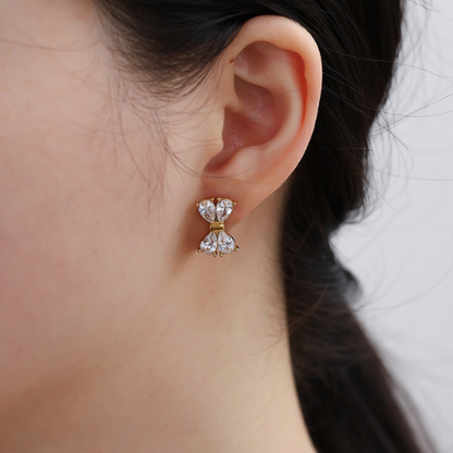 Shiny Bow Studs oorbellen in goud met witte strikvormige zirkonia – elegante oorstekers in het oor gedragen